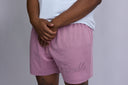 Person wearing pink shorts with 'Gamble' embroidery on a plain background