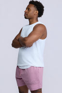 Man wearing a white sleeveless shirt and pink shorts on a light gray background